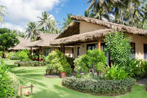 une maison avec une cour d'herbe devant elle dans l'établissement Bamboo Village Beach Resort & Spa, à Mui Ne