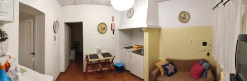 a room with a couch and a kitchen with clocks on the walls at Casinha alentejana in Évora