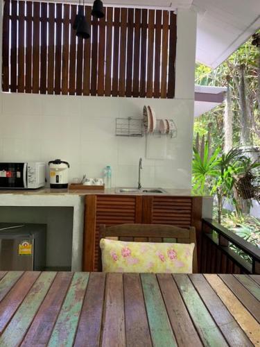 a kitchen with a wooden table and a kitchen with a sink at Benjamin's Hut in Srithanu