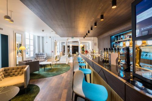 ein Restaurant mit einer Bar mit Stühlen und Tischen in der Unterkunft Aigle Noir Hotel Fontainebleau - MGallery Collection in Fontainebleau