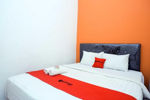 a bed with two red pillows on top of it at RedDoorz @ Kawasan Industri Candi Semarang in Kalibanteng-kidul