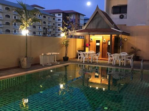 a swimming pool with white chairs and a house at soi2inn in Pattaya Central