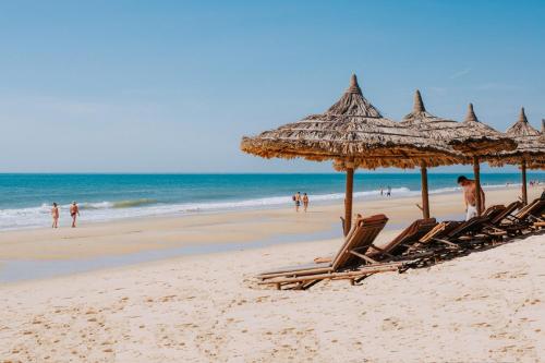 - un groupe de chaises longues et de parasols sur une plage dans l'établissement Bamboo Village Beach Resort & Spa, à Mui Ne