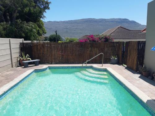 a swimming pool in a backyard with a wooden fence at The Pool Cottage in Fish hoek