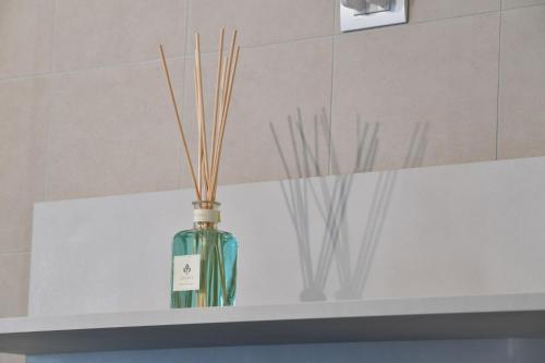 a green bottle with sticks in it sitting on a shelf at Habitat Apartments in Trento