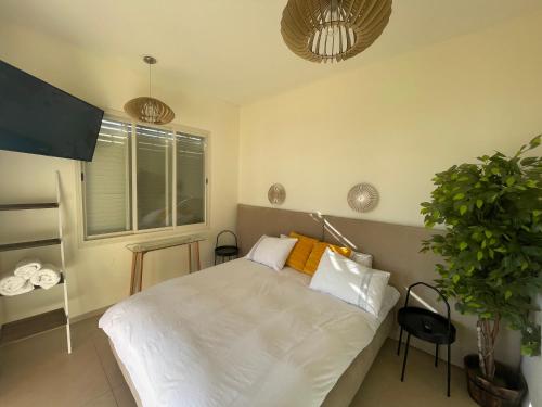 een slaapkamer met een wit bed en een potplant bij נוף המצוק in Poriyya