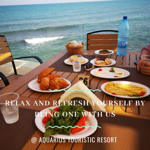 Aquarius Touristic Resort في Al Minyah: طاولة مع أطباق من الطعام والمحيط