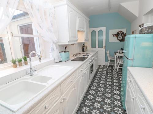 a kitchen with white cabinets and a blue refrigerator at Elm Cottage in Bishop Auckland