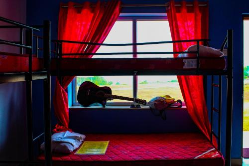a bunk bed with a guitar in a room with a window at HosteLife Gokarna in Gokarna