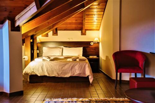 a bedroom with a bed and a red chair at Grand Hotel Dentro in Konitsa