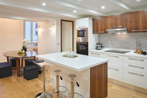 une cuisine avec un comptoir blanc et une table dans l'établissement Sunlight Properties - Palme D Or - 2 Bedrooms, modern holiday rental apartment, hyper central, à Cannes
