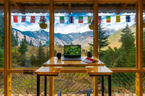 a laptop sitting on a table in front of a window at The Hosteller Shangarh, Sainj Valley in Sainj