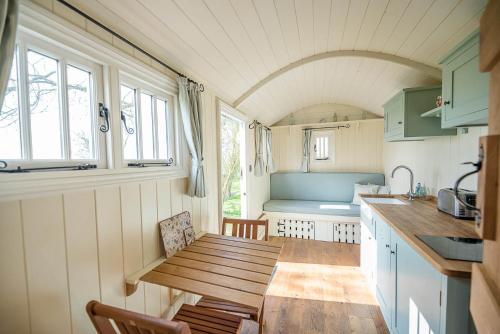 a small kitchen with a wooden table in a caravan at Sage Shepherds Hut Boundary Farm Air Manage Suffolk in Woodbridge