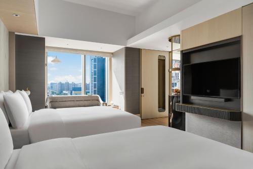a hotel room with two beds and a flat screen tv at InterContinental Kaohsiung by IHG in Kaohsiung