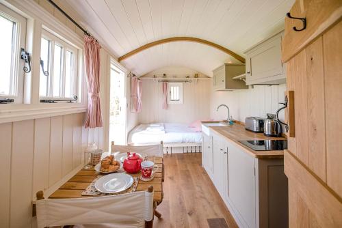 a small kitchen with a table in a caravan at Thyme Shepherds Hut Boundary Farm Air Manage Suffolk in Woodbridge