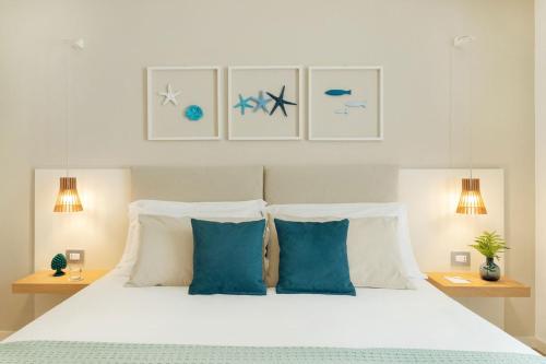 a bedroom with a white bed with blue pillows at Albatros Beach Hotel in Letojanni