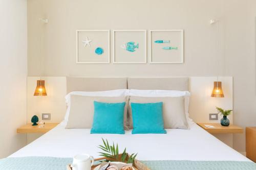 a bedroom with a white bed with blue pillows at Albatros Beach Hotel in Letojanni