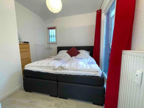 a small bedroom with a bed with a red wall at Schönes Bungalow, Check-In Kontaktlos, Zentral in Duisburg