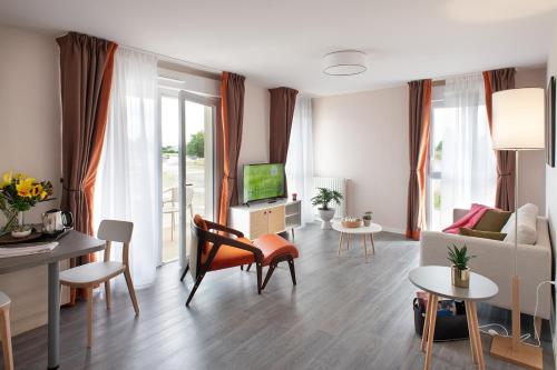 a living room with a couch and a tv at Le Critérium in Écouflant