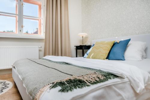 a bed with blue and yellow pillows and a window at Prague Days - Bright Apartments - Fast WiFi - Quiet Area in Prague