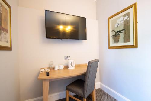 a desk with a chair and a television on a wall at Heart of England, Northampton by Marston's Inns in Daventry