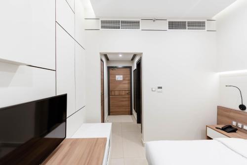 a room with white walls and a tv and a hallway at Resivation Hotel in Dubai