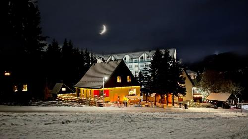 ein Haus im Schnee in der Nacht mit einem Mond in der Unterkunft Ferienwohnung-direkt-am-skihang in Kurort Oberwiesenthal