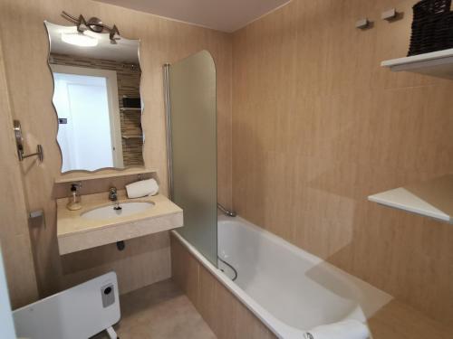 a bathroom with a sink and a tub and a mirror at Apartamento en Sierra Nevada, próximo a pistas y plaza central, vistas increíbles in Sierra Nevada