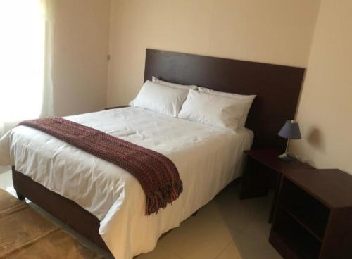 a bedroom with a large white bed with a wooden headboard at Hall's Home in Gaborone