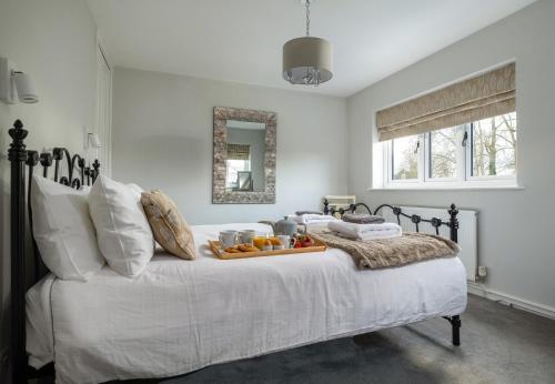 a white bed with a tray of fruit on it at Finest Retreats - Esmor Cottage in Caerwys