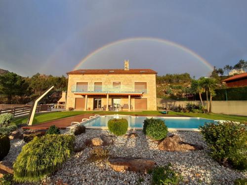a rainbow over a house with a pool at A Ballenera de Caneliñas in Cee