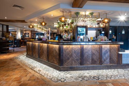 a bar in a restaurant with a wooden counter at Two Rivers Lodge by Marston’s Inns in Chepstow