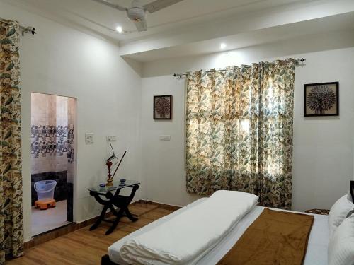 a bedroom with a bed and a table and a window at Hindupura Residency in Sawāi Mādhopur