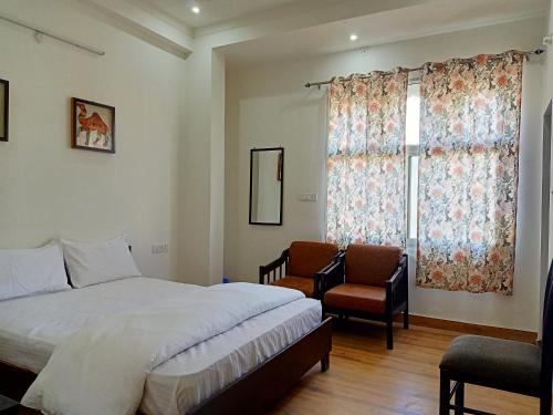 a bedroom with a bed and a chair and a window at Hindupura Residency in Sawāi Mādhopur