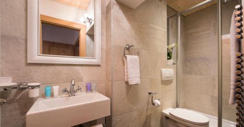 een badkamer met een wastafel, een toilet en een spiegel bij Chalet Taja in Sankt Anton am Arlberg