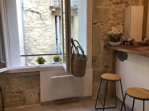 une cuisine avec deux tabourets et une fenêtre dans l'établissement Loft avec beaucoup de cachet centre historique Montpellier, à Montpellier