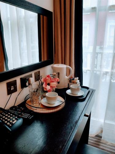 a table with cups and saucers and flowers on it at Hotel Edward Paddington in London