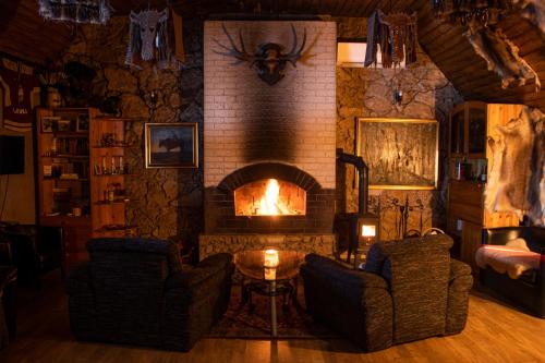 a living room with a fireplace with two chairs and a table at Hunter's Lodge in (( Šarlote ))