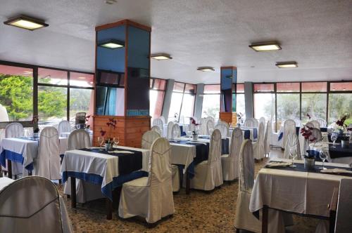 un comedor con mesas y sillas blancas en Hotel Campomar, en Isla