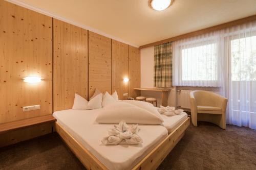 a bedroom with a large bed with white pillows on it at Hotel Enzian Paznaun in See