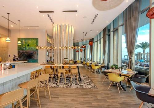 a restaurant with yellow chairs and tables and windows at Lyfe Resort on Miami Hollywood BeachFront by MRA in Hollywood