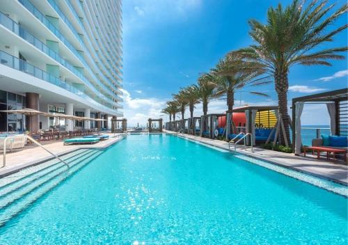 a swimming pool with palm trees and a building at Lyfe Resort on Miami Hollywood BeachFront by MRA in Hollywood