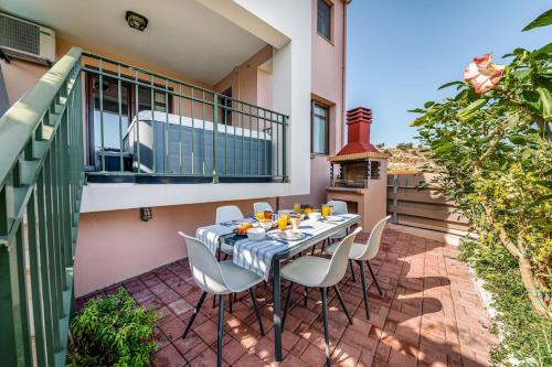 patio con mesa y sillas en el balcón en Mikra Anogia Villas, en Rethymno