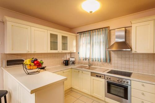 a kitchen with white cabinets and a bowl of fruit on a counter at Mikra Anogia Villas in Rethymno Town