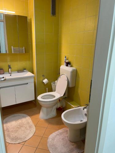 a yellow bathroom with a toilet and a sink at Apartment Host in Tuzla