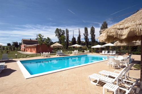 una piscina con sillas blancas y un complejo en Agriturismo Casale Le Selvette, en Ripa