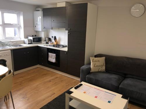 a living room with a couch and a kitchen at 2nd Floor Town Centre Apt with FREE Parking in Loughborough