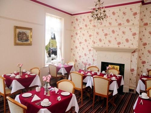 a dining room with tables and chairs and a fireplace at Devonia Express in Eastbourne