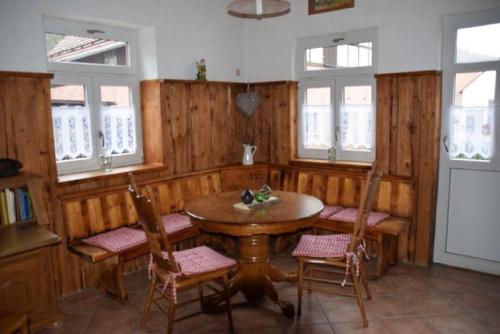 Un comedor con mesa y sillas y ventanas. en Ferienhaus Zur kleinen Kneipe, en Fladungen