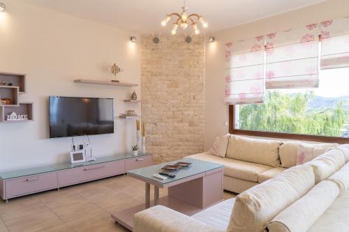 a living room with a couch and a tv at Dolce Evita in Makry Gialos